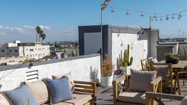 A rooftop terrace with outdoor seating, string lights, and potted plants. - Belmont Shore Peninsula - 2 King Suites 2.5Baths - Roof Deck + Garage - Sleeps 6 (Long Beach)