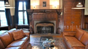 A traditional living room with leather sofas, a fireplace, and wooden paneling. - Architect's Brownstone Mansion 6B6B, Porch, Garden (Minneapolis)