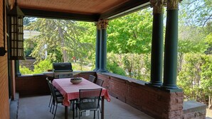 An outdoor patio with a table and chairs, a grill, and a view of greenery. - Architect's Brownstone Mansion 6B6B, Porch, Garden (Minneapolis)