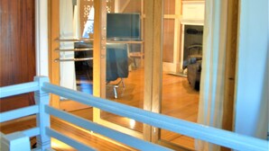 A wooden-framed sliding door leading to a room with a white railing and a wooden floor. - Architect's Brownstone Mansion 6B6B, Porch, Garden (Minneapolis)