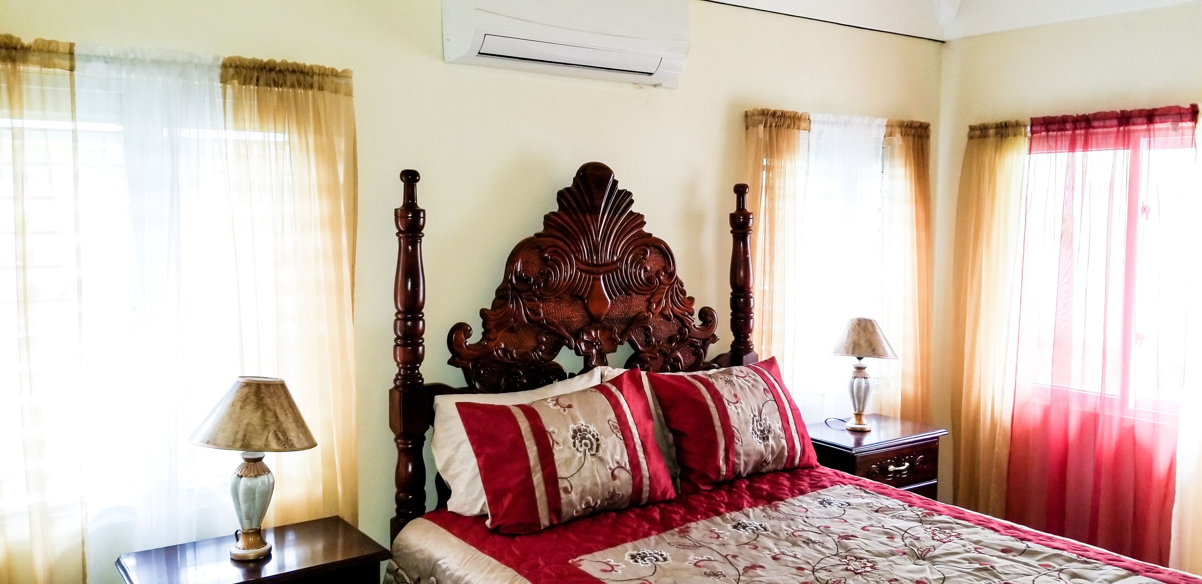 A bedroom with a wooden bed, beige walls, and curtains.