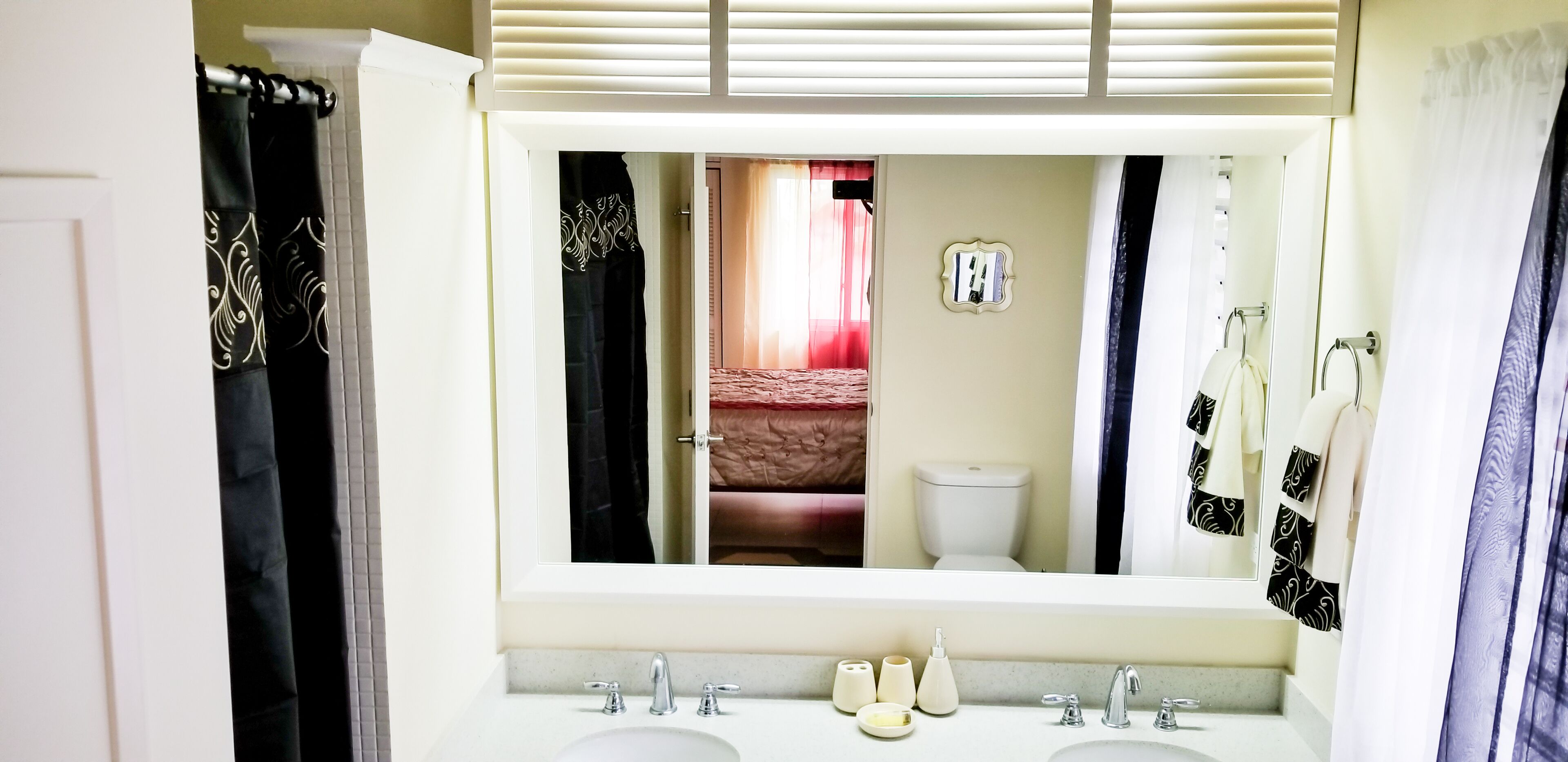 Une salle de bain avec un grand miroir, deux lavabos et des toilettes.