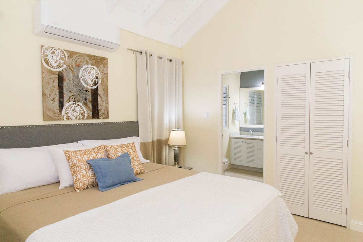 A hotel room with a bed, a nightstand, a lamp, a mirror, and a wardrobe.