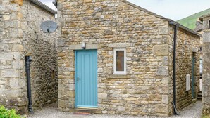 A stone building with a blue door, a small window, and a satellite dish on the left.
