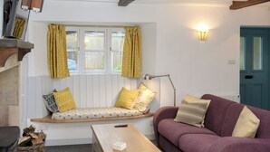 A cozy living room with a bench, a purple sofa, a wooden table, and a lamp.