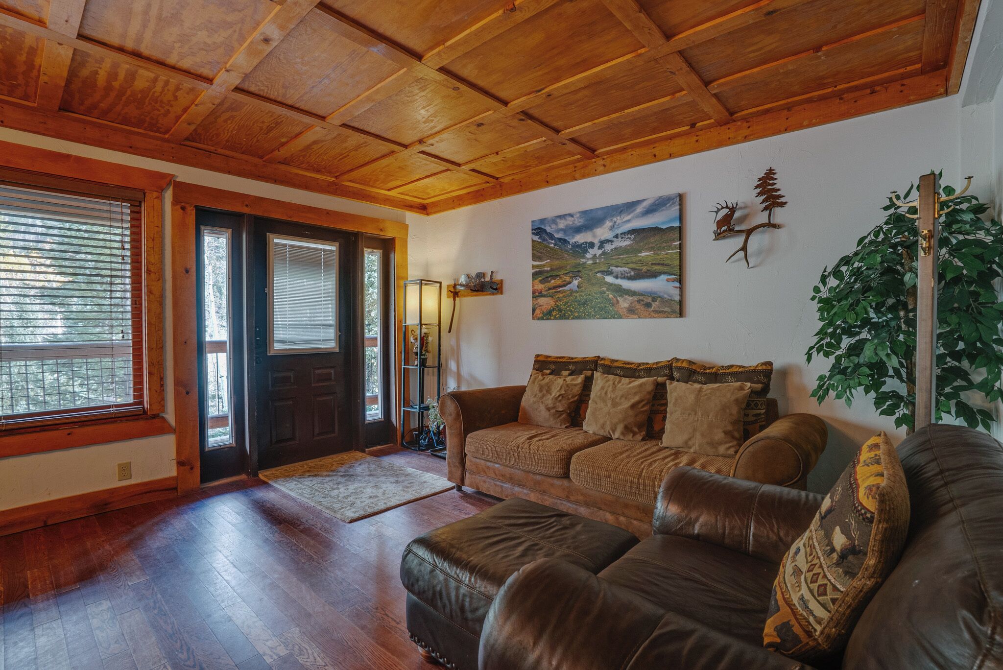 Un accogliente soggiorno con soffitto in legno, un divano in pelle marrone, un tavolino in legno e un quadro raffigurante un paesaggio.