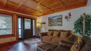 Ein gemütliches Wohnzimmer mit Holzboden, einem braunen Ledersofa, einem Couchtisch aus Holz und einem Landschaftsbild.