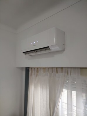 A white air conditioning unit mounted on a wall with a control panel displaying temperature settings. - Room in homestay (Villa Real)