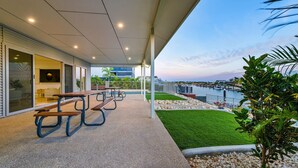 Un espacio al aire libre techado con mesas de picnic y vista al agua.