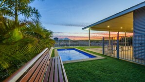 Un patio trasero con piscina, terraza de madera y zona de patio cubierta.