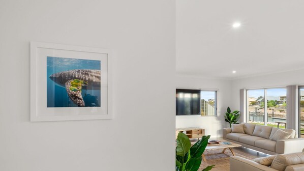 Uma sala de estar moderna com uma janela ampla, um quadro na parede e um sofá bege.