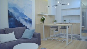 A modern living room with a grey sofa, a round white table, and a large abstract painting. - Last Floor Apartment - City Center Old Town / Stare Miasto (Stare Miasto)