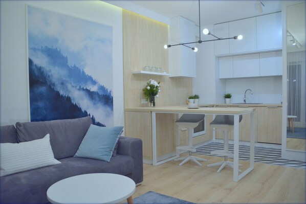 A modern living room with a grey sofa, a round white table, and a large abstract painting. - Last Floor Apartment - City Center Old Town / Stare Miasto (Stare Miasto)