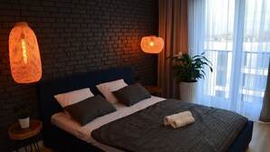 A modern bedroom with a brick wall, a dark blue headboard, and two hanging lamps. - Last Floor Apartment - City Center Old Town / Stare Miasto (Stare Miasto)
