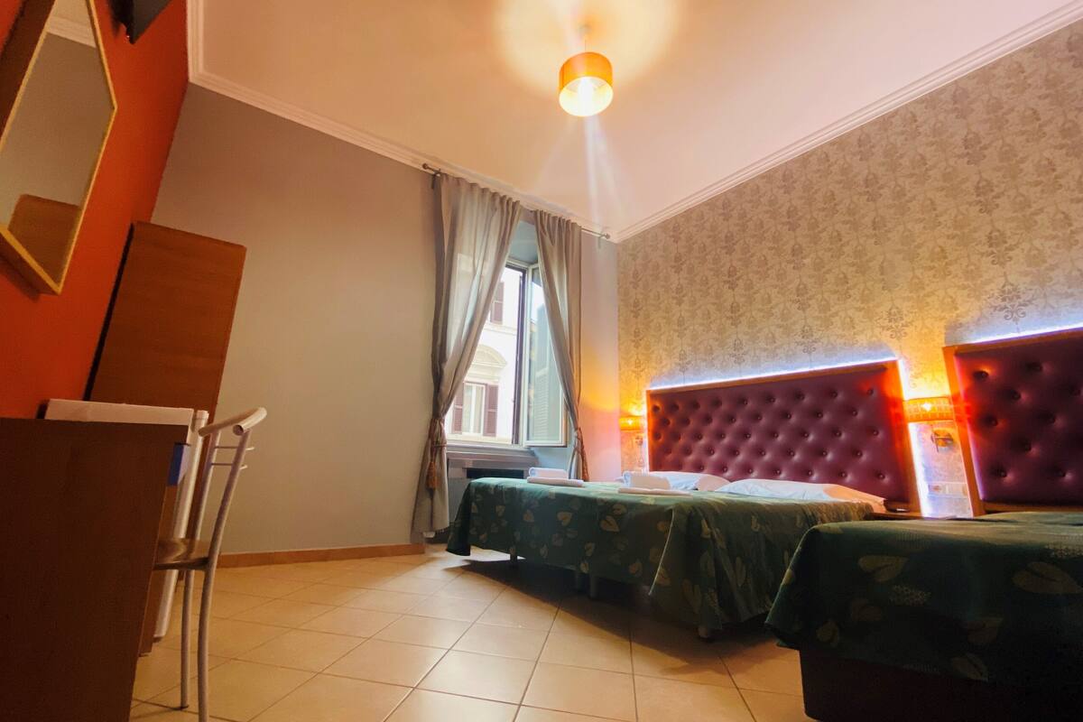 A hotel room with two beds, a desk, and a chair.