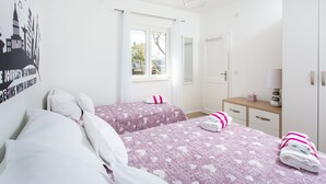 A hotel room with two beds, a window with curtains, a bedside table with a lamp, and a wall with a cityscape poster. - Apartments L&M - One Bedroom Apartment with Terrace (Dubrovnik)