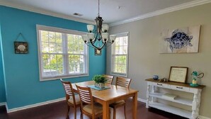 A dining area with a wooden table and chairs, a chandelier, and a white console table with drawers. - Quick Walk to the Beach!! (North Myrtle Beach)