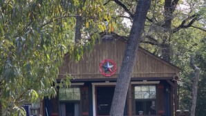 Una cabaña rústica con fachada de madera, un porche y un jacuzzi.