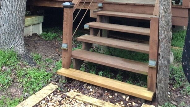 Una cabaña de madera con un porche, una escalera y un logo de estrella en la fachada.