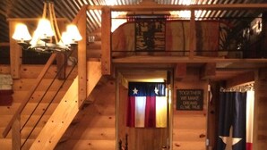 Un acogedor interior de cabaña de madera con una escalera, un sillón de cuero y un letrero que dice "TOGETHER WE MAKE DREAMS COME TRUE".
