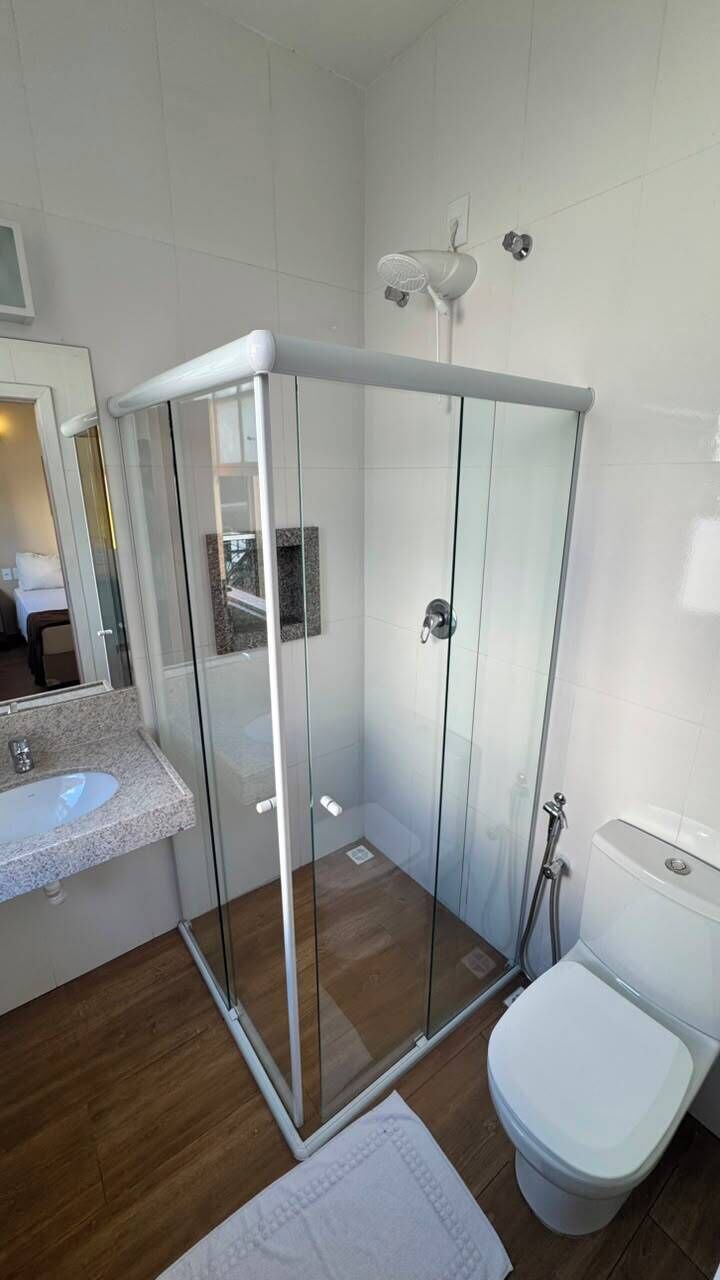 A modern bathroom with a glass-enclosed shower, a white toilet, and a sink with a marble countertop.