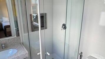 A modern bathroom with a glass-enclosed shower, a white toilet, and a sink with a marble countertop.