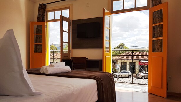 A hotel room with a bed, a desk, and a TV. - Pousada Imperial Cidade (Ouro Preto)