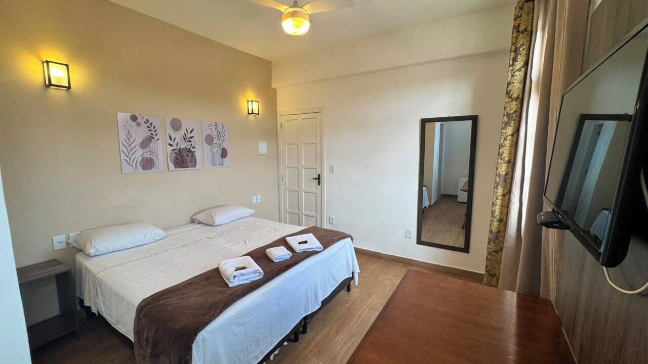 A hotel room with a bed, bedside tables, a flat-screen TV, and artwork on the wall.