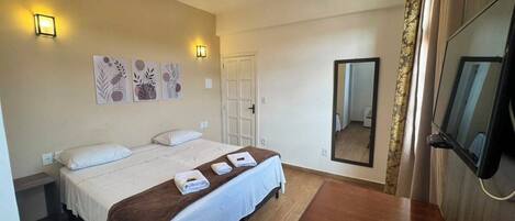 A hotel room with a bed, bedside tables, a flat-screen TV, and artwork on the wall.
