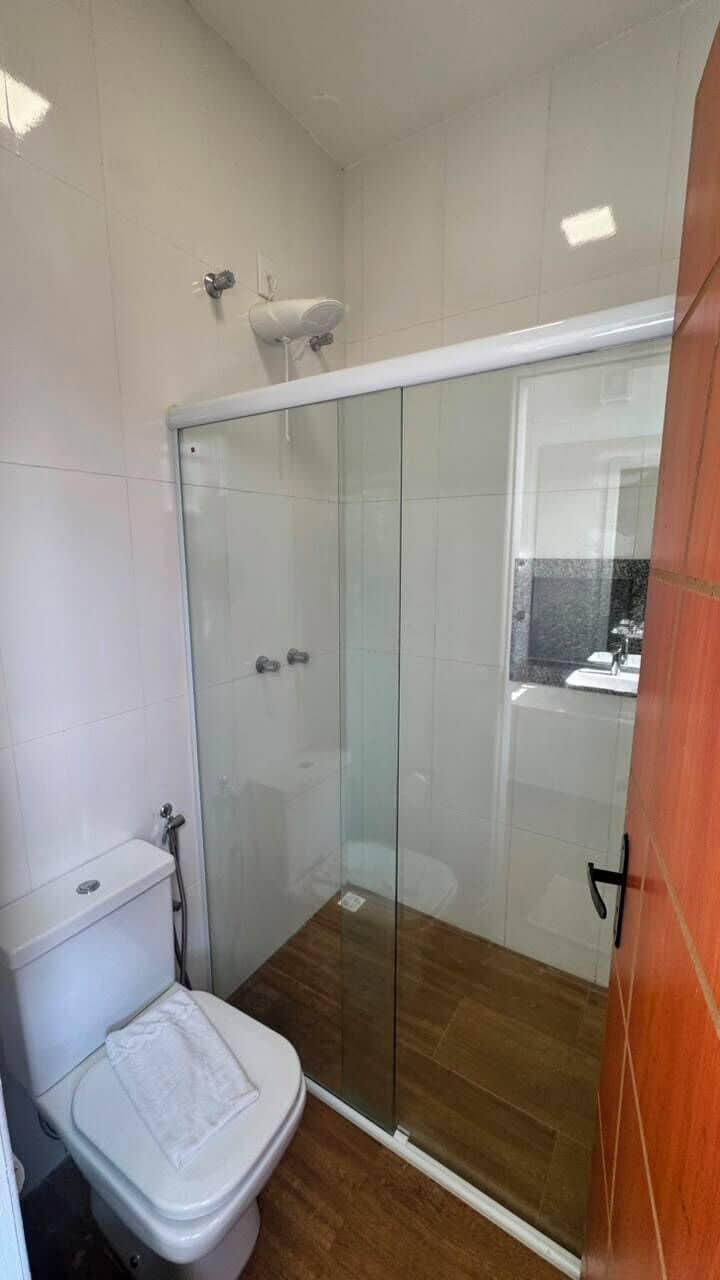 A bathroom with a glass-enclosed shower, a toilet, and a sink.