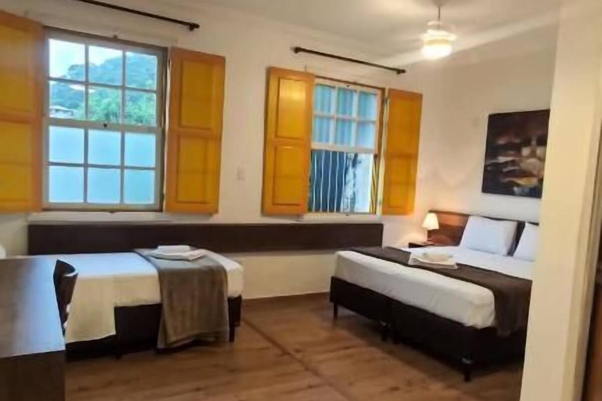 Ein Zimmer mit zwei Betten, einem Tisch und einem Fenster mit Fensterläden.