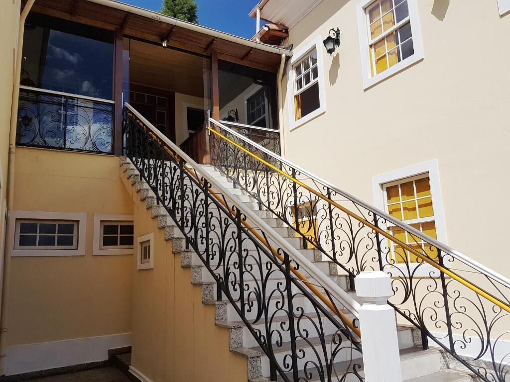 Una escalera con barandillas negras ornamentadas y una pared amarilla.