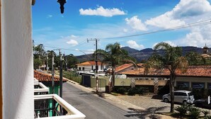 A balcony with a view of a street, buildings, and mountains in the distance. - Pousada Imperial Cidade (Ouro Preto)