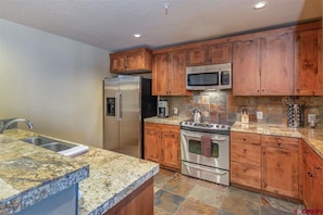 Enjoy cooking in this well-equipped kitchen with a double sink, refrigerator, microwave, and oven.