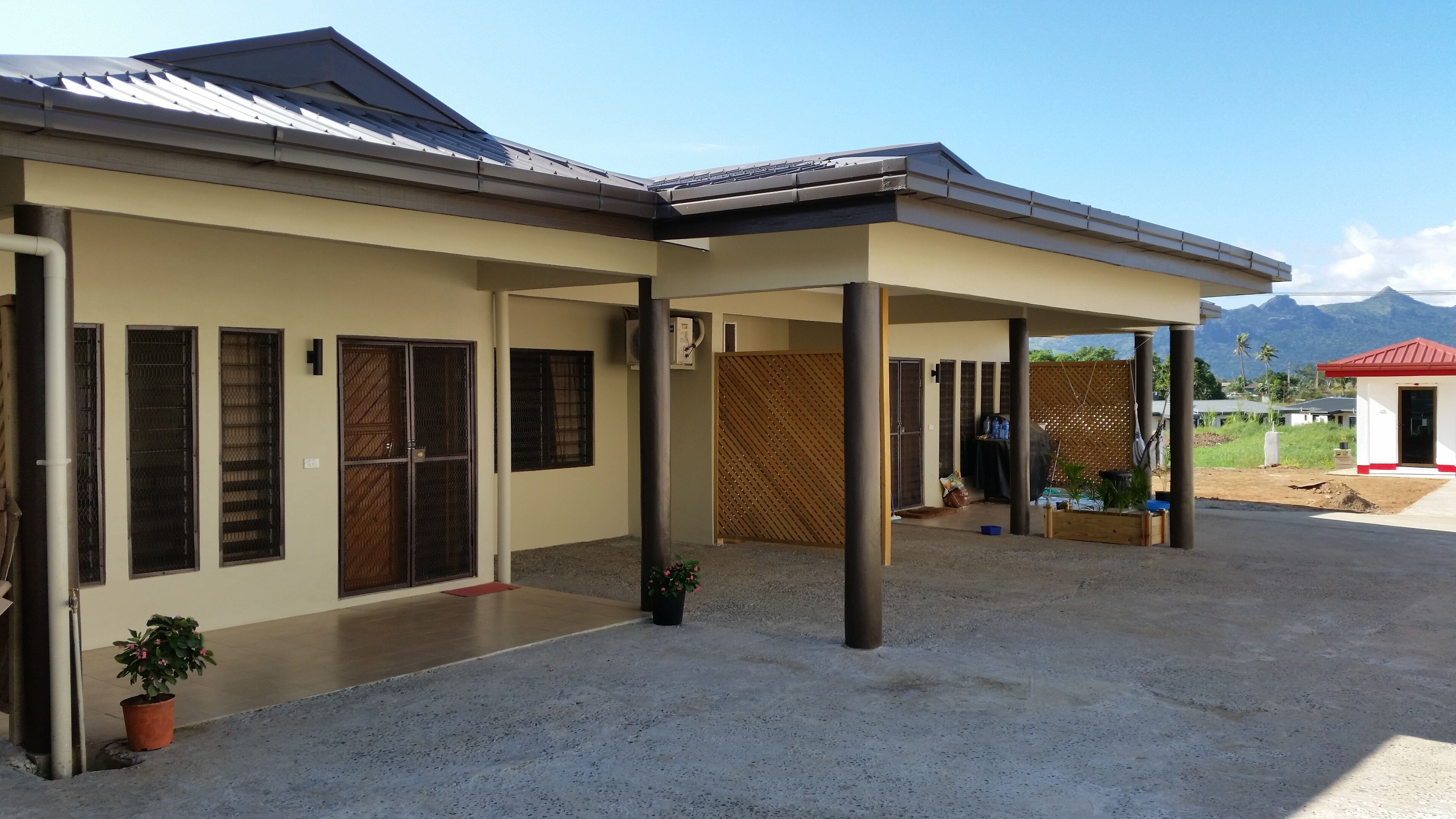 A two-story house with a covered patio area, a fenced yard, and a mountain backdrop.