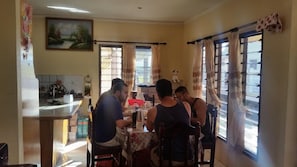 Uma área de refeições com mesa, cadeiras e bancada de cozinha.