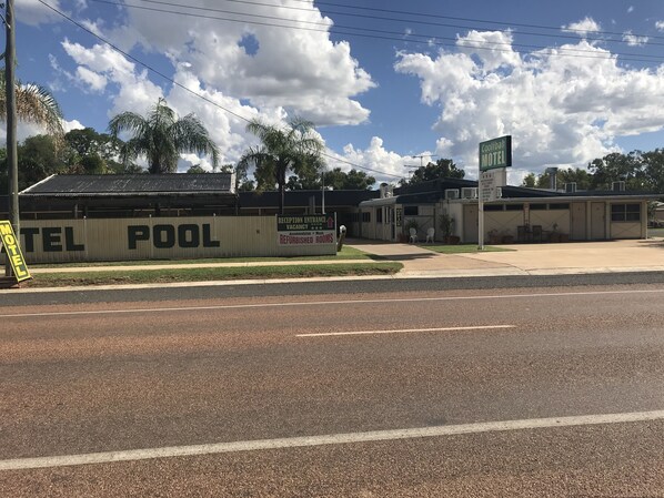 Un motel avec une grande enseigne publicitaire indiquant « Piscine du motel » et « Entrée de la réception ».
