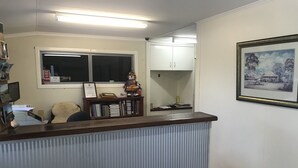 Een receptiegedeelte met een balie, een boekenkast, een raam en een ingelijste foto aan de muur.