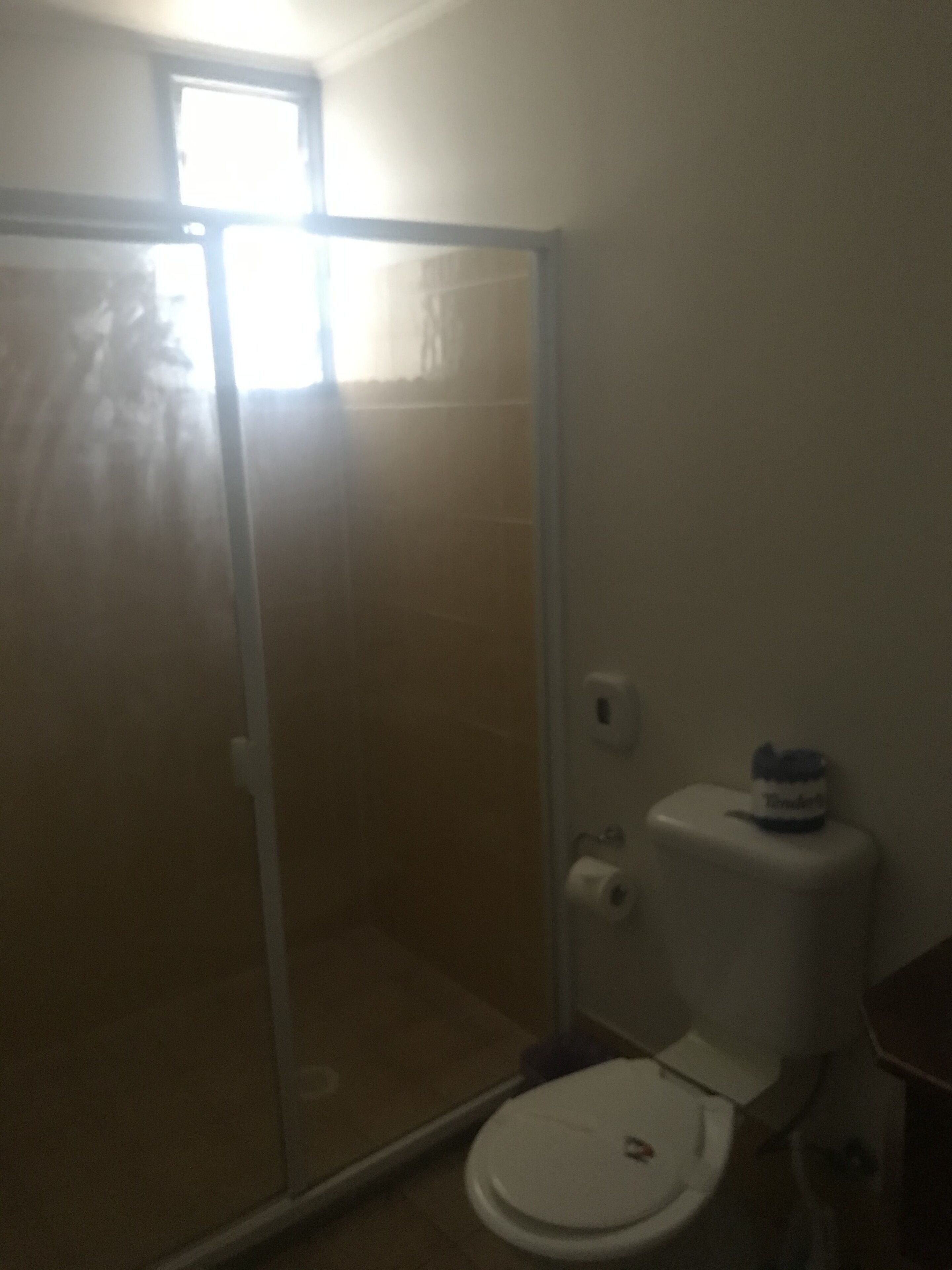 Ein Badezimmer mit Toilette, einer Glasdusche und einem kleinen Fenster.