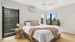 Un dormitorio moderno con una cama grande, ventilador de techo y vistas al exterior.