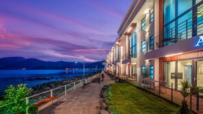 A hotel with a stone pathway leading to a balcony overlooking a body of water and mountains. - Namhae Lounge 32 Resort A (Namhae)