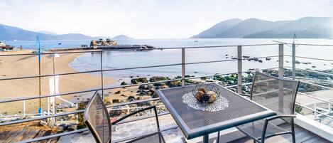 A balcony with a view of a beach and the sea.