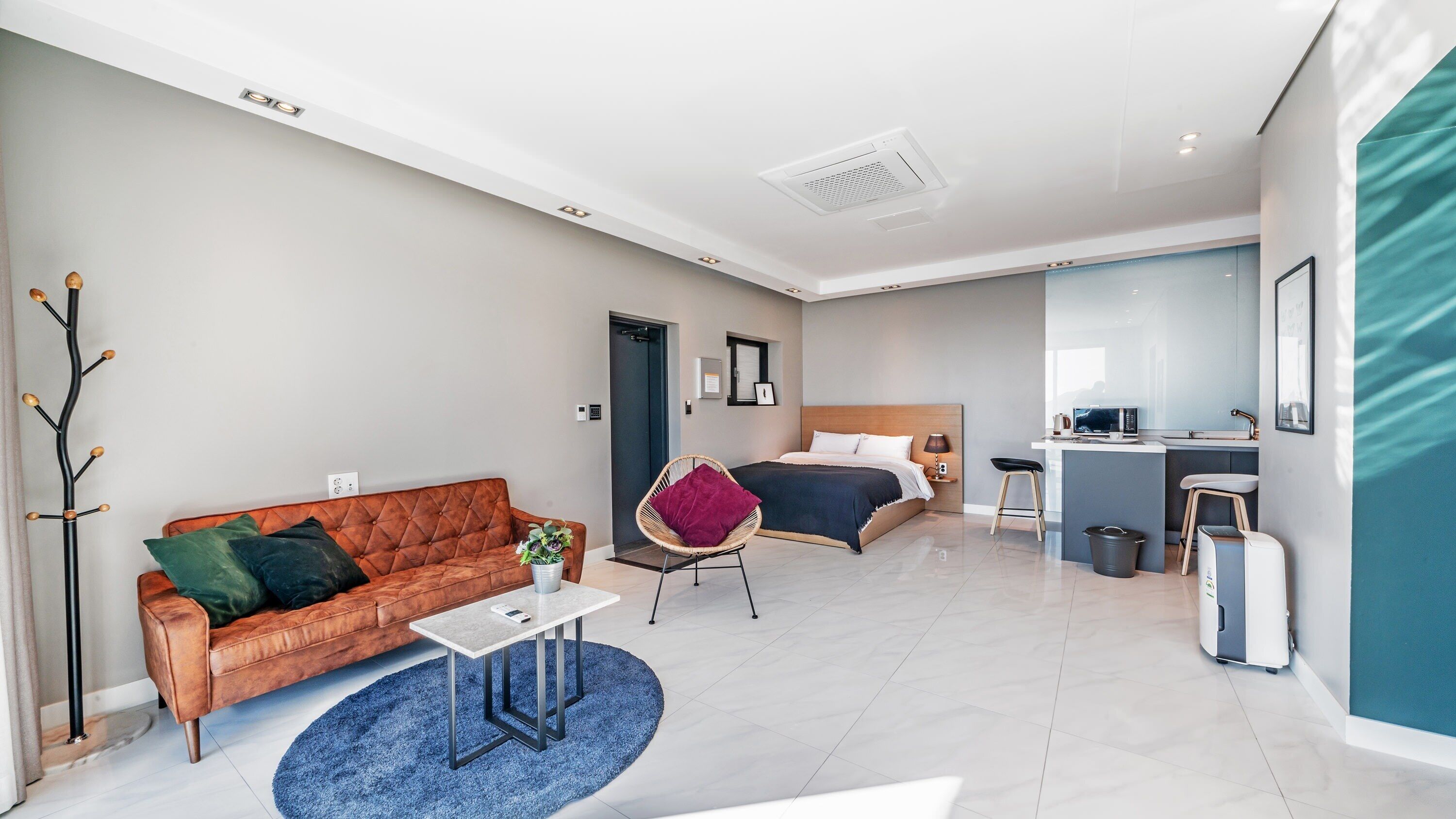 Une chambre d’hôtel moderne comprenant un espace de vie, une chambre séparée, une kitchenette et une salle de bain.