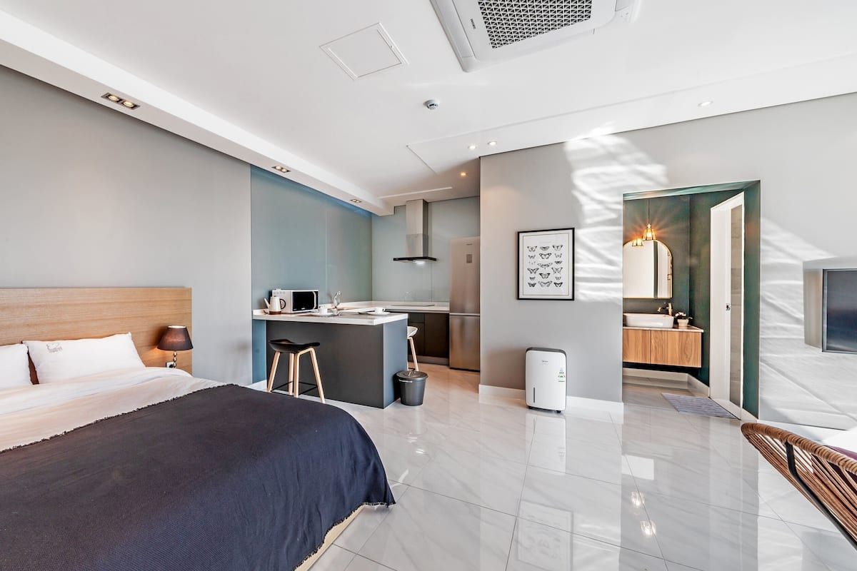 Et moderne hotelværelse med seng, tekøkken, badeværelse og siddeområde.