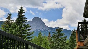 A mountain view with a prominent peak, surrounded by evergreen trees and a clear sky. - Kananaskis Getaway, 1Br. Condo in the mountains (Dead Man's Flats)
