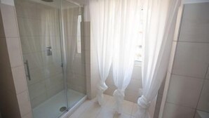 A bathroom with a glass shower enclosure, white curtains, and tiled flooring. - Ad 2015 Guesthouse (Rome)