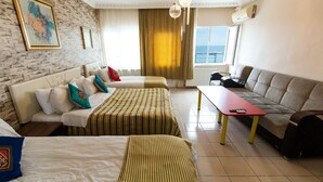 A hotel room with two beds, a sofa, a table, and a view of the sea. - White Palace Apart (Istanbul)