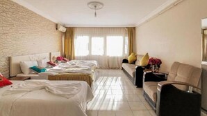 A hotel room with two beds, a sofa, a chair, a small table, and a window with curtains. - White Palace Apart (Istanbul)