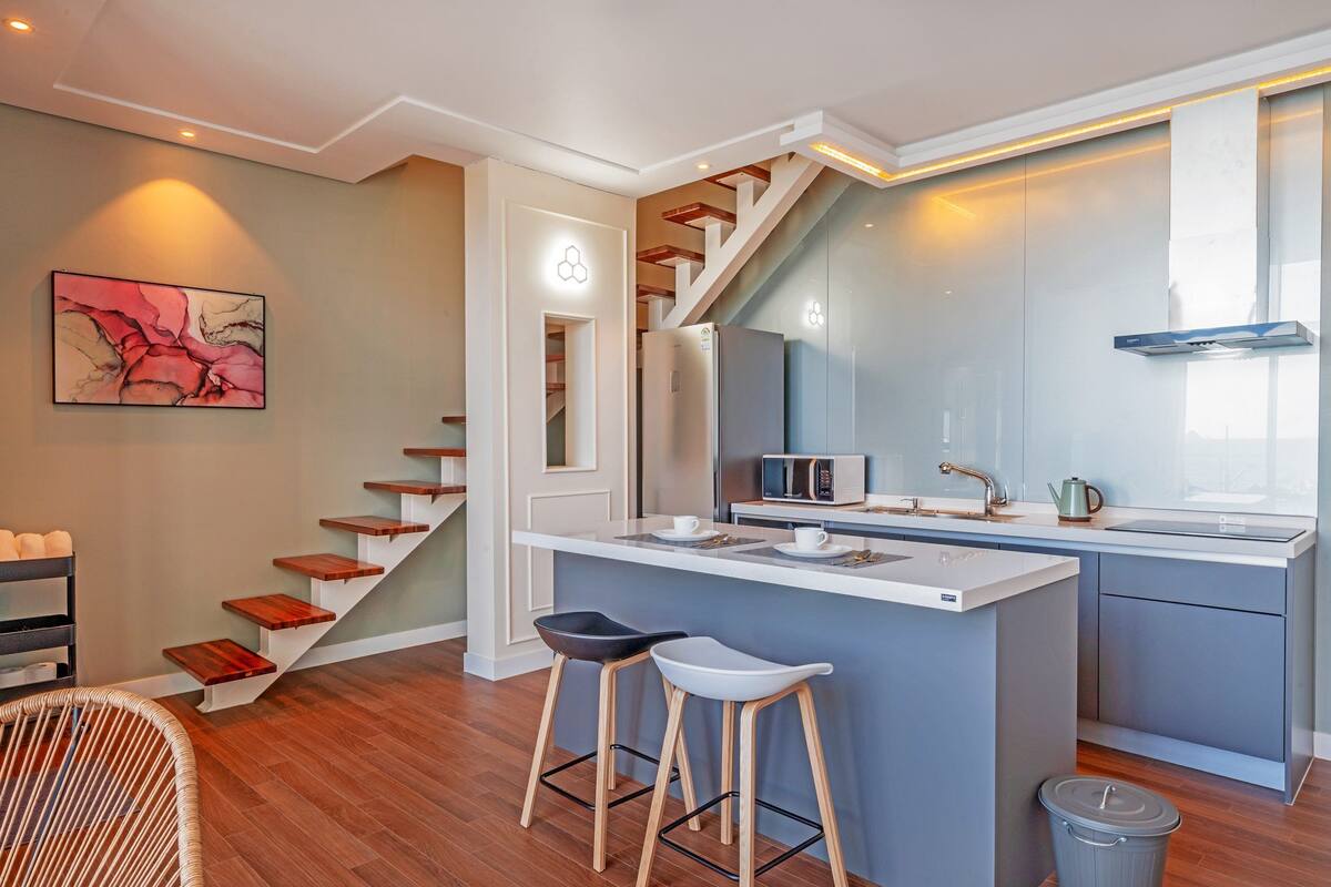 A modern kitchen with a central island, a microwave, and a kettle.