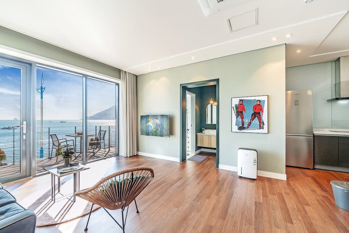 A spacious living area with a large balcony overlooking a scenic ocean view, a modern kitchen, and a dining area with a view.